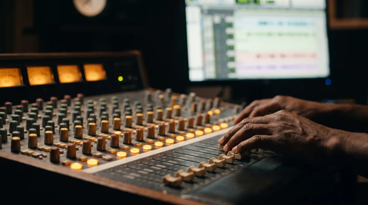 Hands on the faders of a mixing console